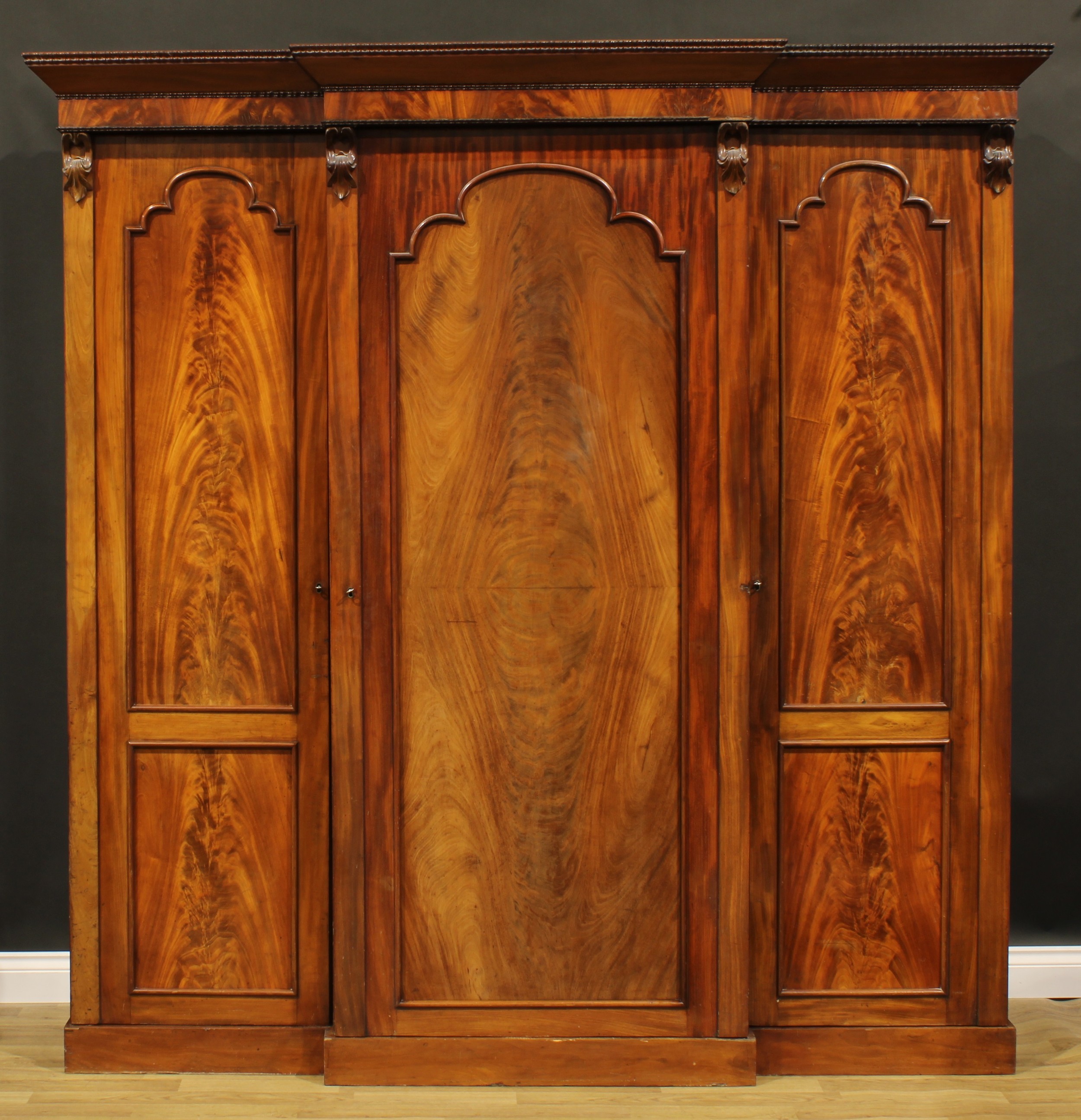 A Victorian mahogany break-centre wardrobe, outswept cornice with reel edge above three panel doors,