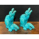 A pair of Burmantofts Faience models, of dragon type mythical beasts, glazed throughout in