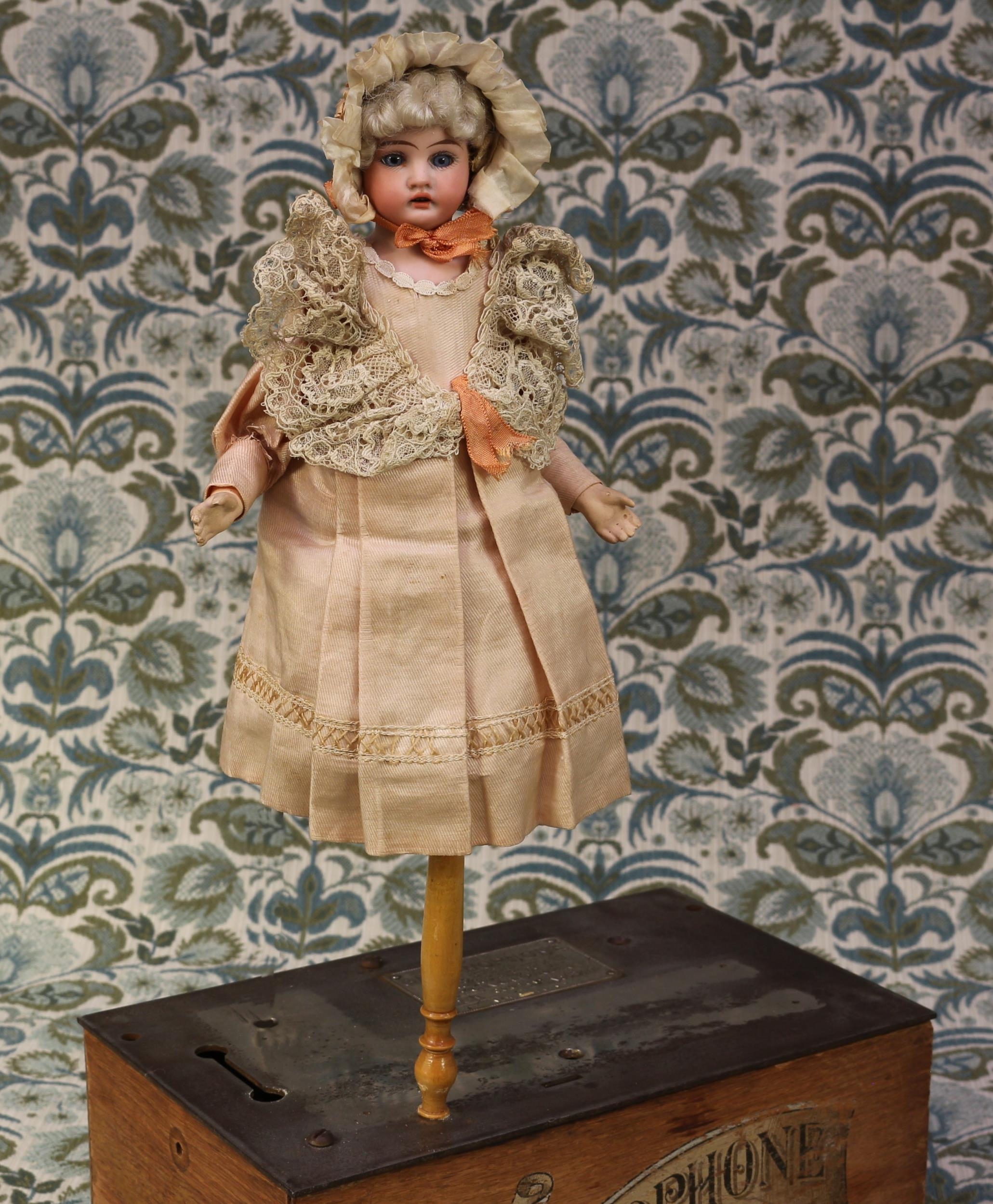 An Armand & Marseille (Germany) bisque shoulder head musical marotte doll and candy container, the
