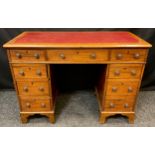 An early 20th century mahogany reproduction pedestal desk, of small proportions, inset red leather