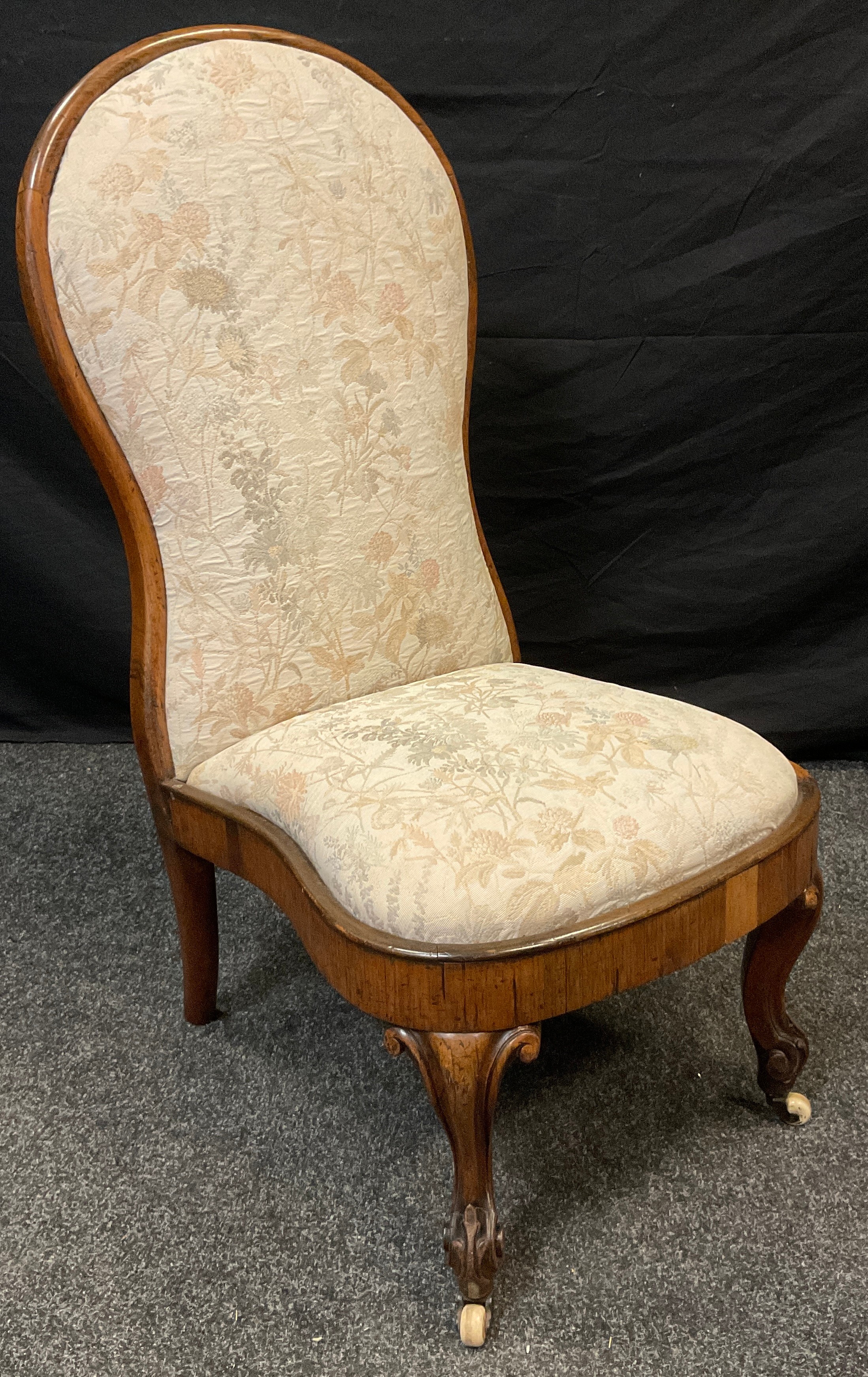 A Victorian rosewood nursing chair, carved cabriole legs, ceramic casters, 95cm high, c.1870.