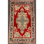 A Central Persian Qum rug / carpet, ornate medallion within a rich red field, stylised floral margin