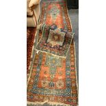 A mid 20th century Middle Eastern woollen runner carpet / rug, hand-knotted in tones of red, blue,