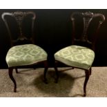 A pair of late Victorian carved mahogany salon chairs, floral rail and splat, stuffed over seat,