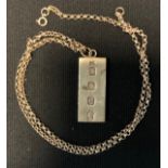A silver ingot pendant necklace with rolo link chain.