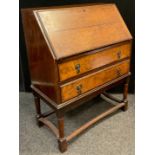 A mid 20th century oak bureau, fall top with fitted interior, above two long drawers, turned