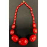 A graduated cherry amber coloured resin bead necklace, beads ranging from approx 13mm to 43mm