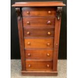 A late 19th early 20th century Wellington chest, six graduated short drawers, carved pilaster