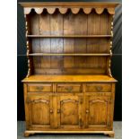 A Titchmarsh and Goodwin style oak dresser, plate rack top, above three short drawers and three