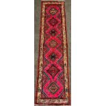 A North west Persian Heriz runner carpet, hand-knotted with a central row of seven diamond form