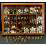 A collection of thimbles in a table top display case, various designs and materials including