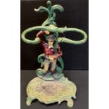 A Cast iron stick/umbrella stand. as a standing man, shell drip pan base, painted in tones of red,