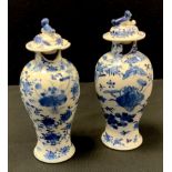 A pair of Chinese kangxi porcelain blue and white jars and covers, painted with traditional floral