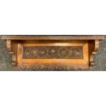 An Arts and Crafts carved oak wall shelf / book-trough, 28cm high x 76.5cm wide x 18cm.