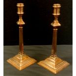 A pair of George III copper candlesticks, plain sconce above offset neck, tapering column, stepped