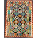 A Turkish Anatolian Kilim rug / carpet, knotted in vibrant tones of red, turquoise, indigo, and