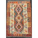 A Turkish Anatolian Kilim rug / carpet, knotted in bright tones of red, orange, green, and cream,