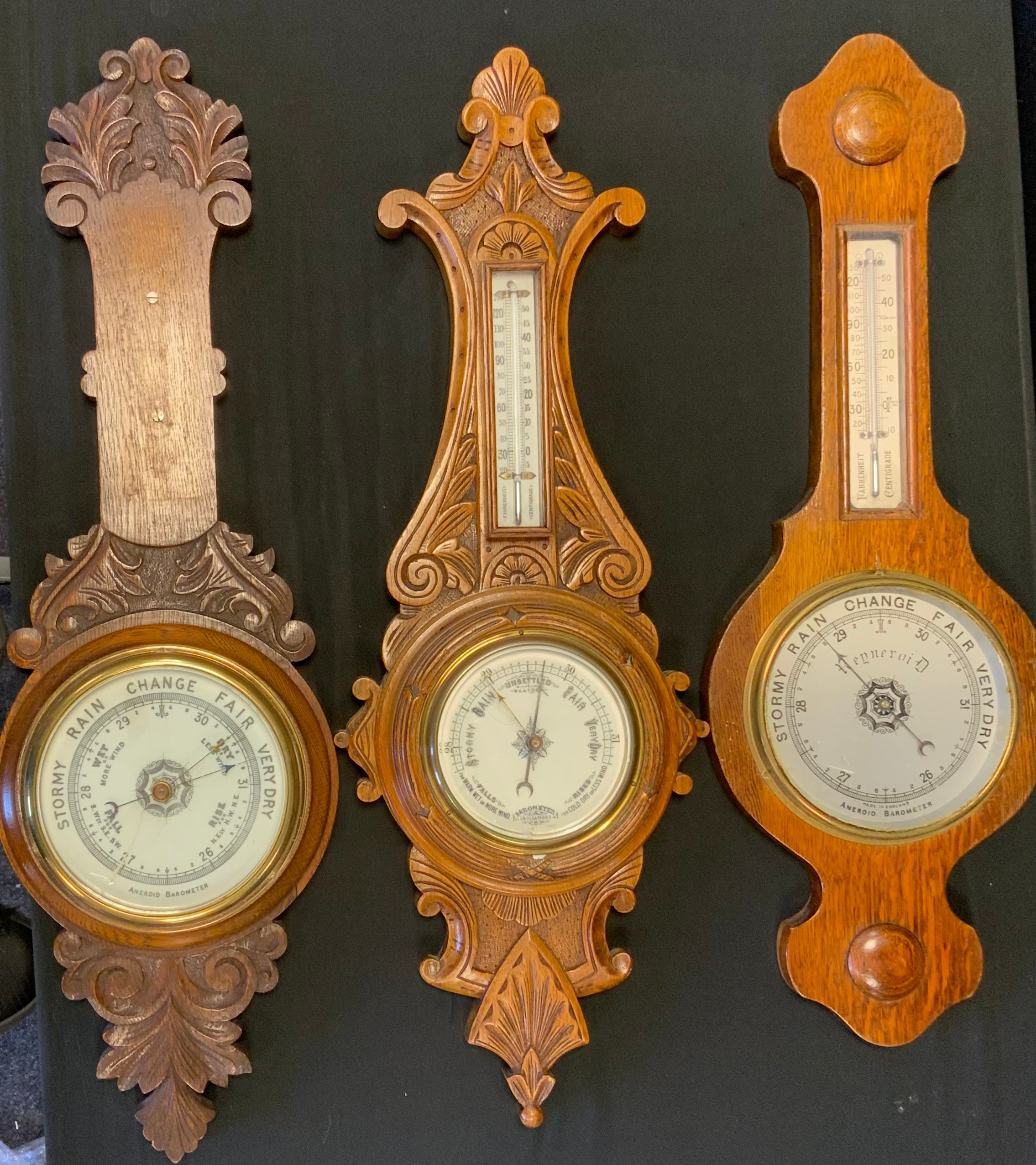 A carved oak framed aneroid barometer thermometer, cream registers, 72cm long; others (3)