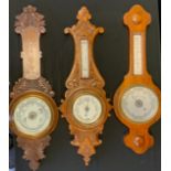 A carved oak framed aneroid barometer thermometer, cream registers, 72cm long; others (3)