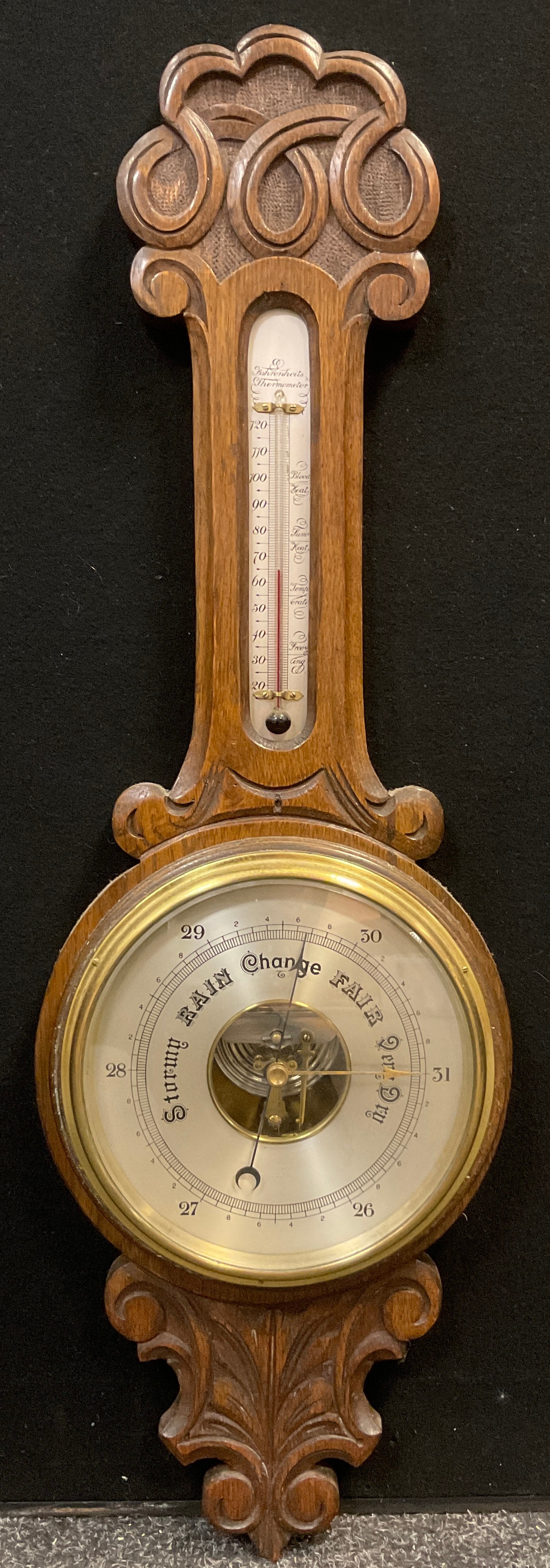 An early 20th century Android Barometer, carved oak case , silvered thermometer and barometer