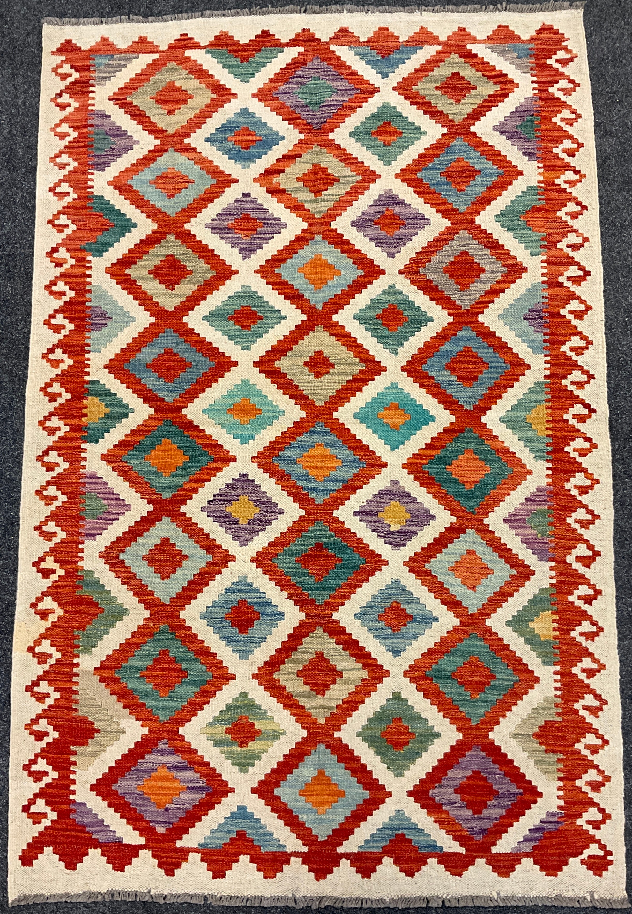 A Turkish Anatolian Kilim rug / carpet, knotted in vibrant tones of red, jade green, orange, and