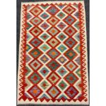 A Turkish Anatolian Kilim rug / carpet, knotted in vibrant tones of red, jade green, orange, and