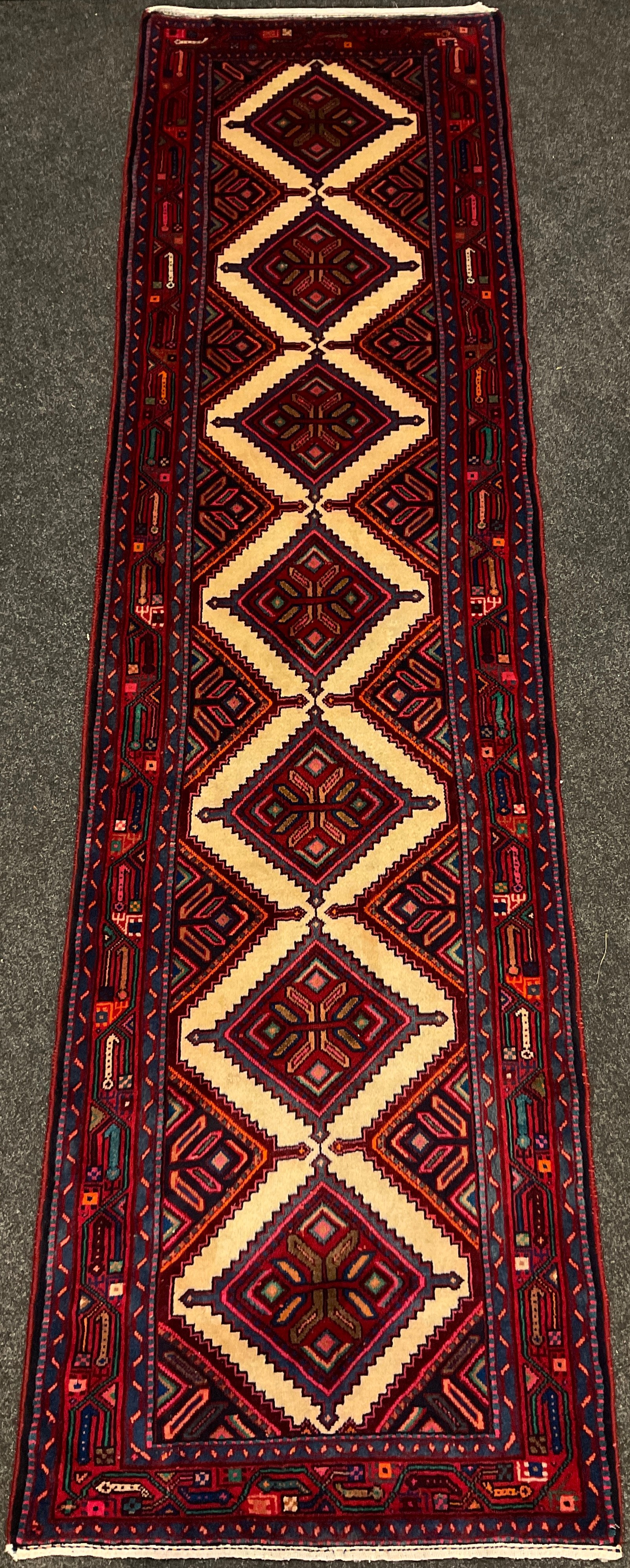 A North West Persian Hamadan runner carpet, hand-knotted in tones of red, blue, turquoise and cream,