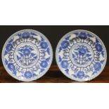 A pair of Chinese shaped circular dishes, painted in tones of underglaze blue with flowers and