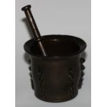 A 17th/18th century Islamic bronze pestle and mortar, flared rim, the side with geometric lugs,