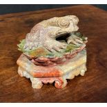 A Chinese soapstone carving, of a toad, upon a lotus, octagonal base, 10cm wide