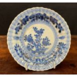A Chinese fluted shaped circular dish, painted in tones of underglaze blue with flowers and rock