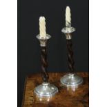 A pair of Arts and Crafts silver and oak candlesticks, spirally turned pillars, domed circular