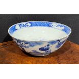 A Chinese circular bowl, playing in tones of underglaze blue with figures in a monumental landscape,