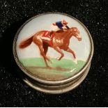 A silver and enamel pill box, the hinged cover decorated with a horse and jockey