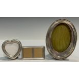 A silver oval photograph frame, Birmingham 1909; another, heart shaped, marked 925; a miniature