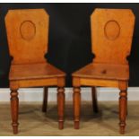 A pair of Victorian oak hall chairs, each with a shaped rectangular back with vacant oval crest