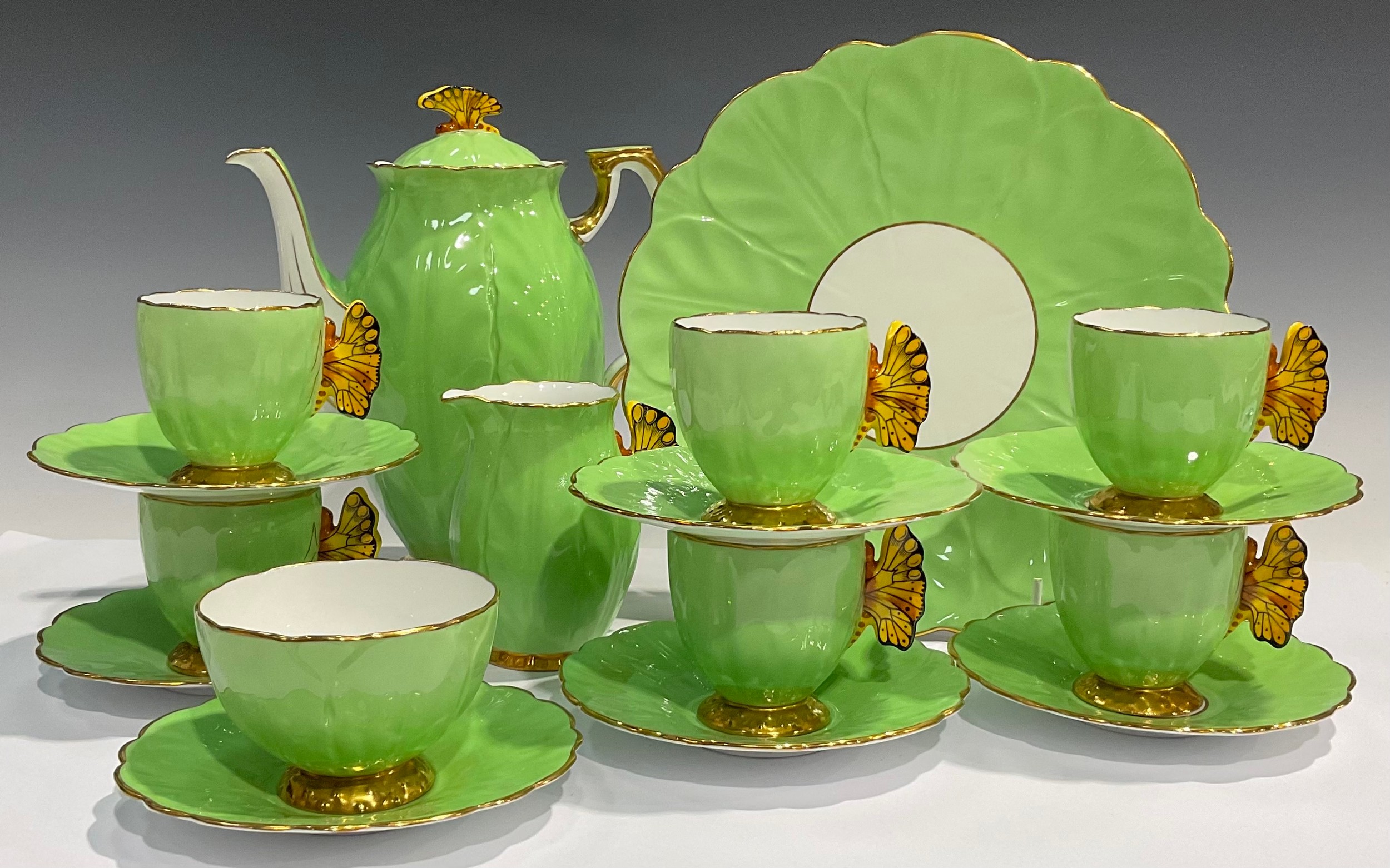 An Art Deco Aynsley coffee set for six, modelled with butterfly handles in yellow, apple green