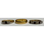 An 18ct gold wedding band, ring size M/N, marked 750; an 18ct gold diamond and sapphire three