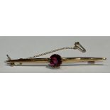 An 18ct gold bar brooch set, set with a single facetted garnet, safety chain, 6cm, marked 18ct, 4.4g