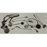 A silver locket on chain; another; silver lapel pin; silver bracelet; other silver and silver