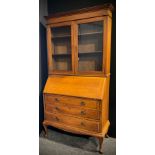 An early 20th century oak bureau bookcase, fall door to bureau top, graduated drawers, cabriole