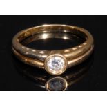 A diamond and 18ct gold solitaire ring, the brilliant cut stone bezel set, divided shank, the