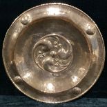 A large Arts and Crafts circular copper dish, embossed with scrolling motifs and bosses, stamped JP,