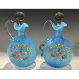 A pair of Victorian opaque blue Vaseline glass decanters, painted with summer flowers in bright