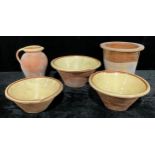 A graduated set of three 19th century terracotta pancheon bowls, cream slip glazed interior, the