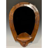 An early 20th century horseshoe shaped walnut looking glass, bevelled mirror plate, with single