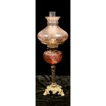 A late 19th century oil lamp, cranberry glass reservoir, pink tinged shade, Duplex twin burner,