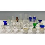 A collection of early to mid 20th century glass and porcelain eyebaths, some green and blue glass;