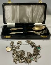 A silver christening fork and spoon set, Birmingham 1958, 36g, cased; a silver curb link charm