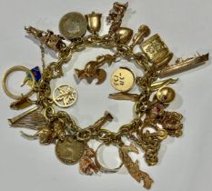 A 9ct gold curb link charm bracelet, assorted 9ct gold charms including, ape, cruise ship, horse and